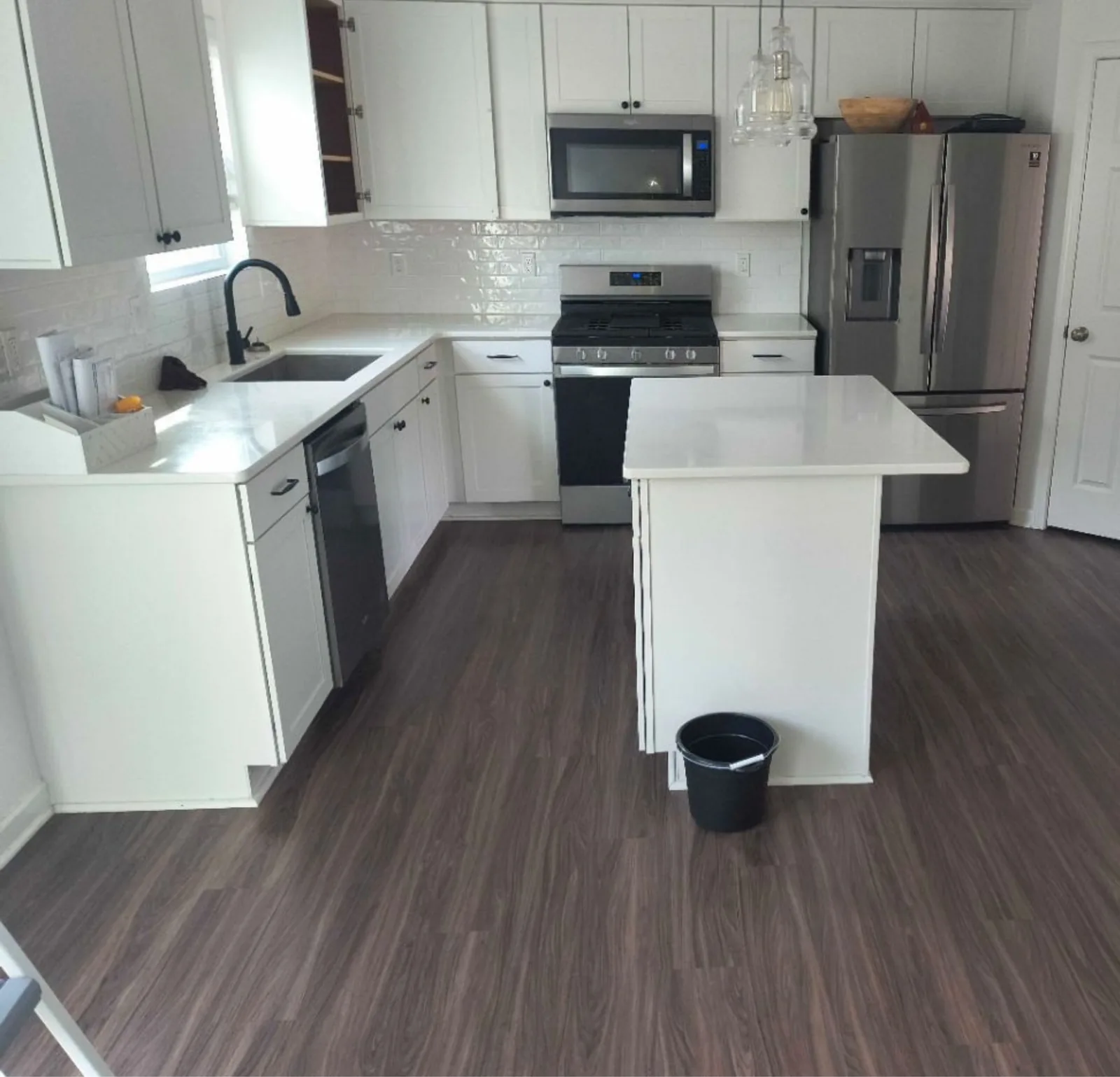 Cleaned white kitchen with quartz island and stainless appliances — Verde Luxe Cleaning